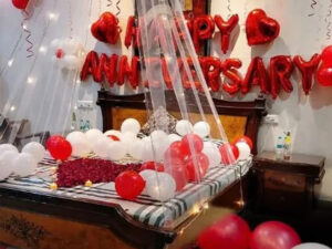 Anniversary decoration with bed canopy, heart foil balloon, tea light candle and rose petals