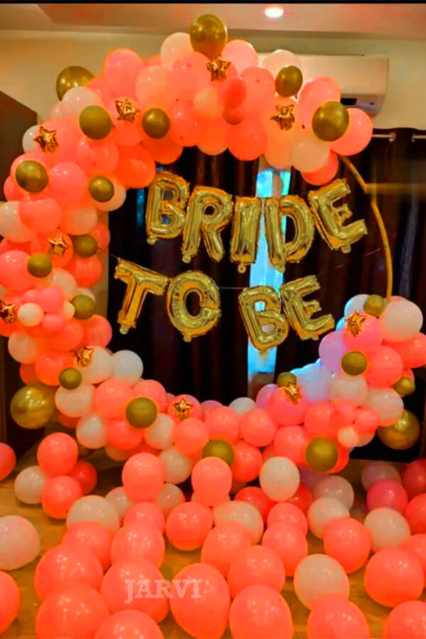 Bachelorette decoration includes a ring-shaped metal stand, pastel balloons, bride-to-be foil, gold chrome balloons, and balloons on the ground