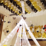 Canopy birthday decoration with fairy lights, heart and happy birthday foil, balloons on ceiling, floor and wall and frilly ribbons