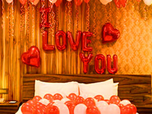 wedding decoration with i love you red alphabet foil balloon, red heart shaped balloons, red balloons hanging from the ceiling and spread on the bed