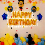 mickey mouse birthday decoration with happy birthday foil balloon alphabet letter, balloons which are in black, red and yellow on the wall and floor, mickey mouse paper cutouts, mickey mouse round foils and star foils