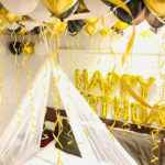 Birthday room decoration with stunning canopy, happy birthday foil, air filled balloons on the floor and ceiling and rose petals decor all around the room