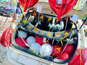 Birthday inside car decoration with happy birthday bunting, red heart shape foil, and metallic balloons spread on car boot