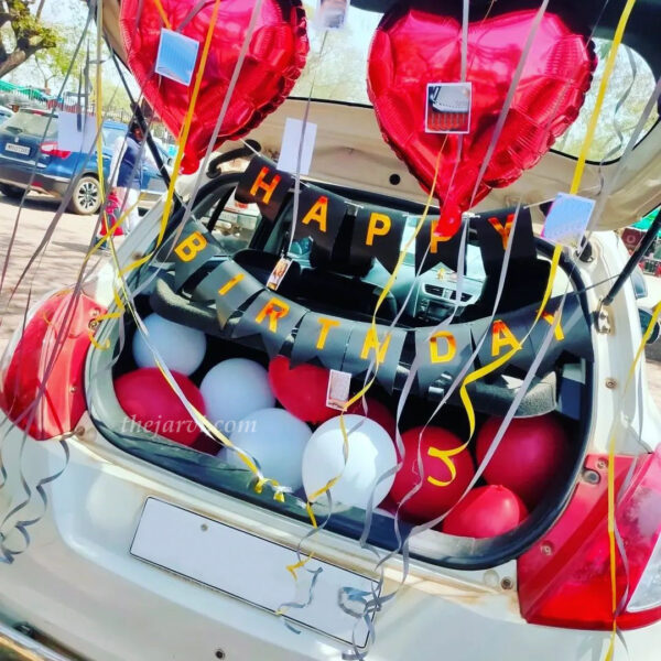Birthday inside car decoration with happy birthday bunting, red heart shape foil, and metallic balloons spread on car boot