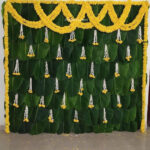 Banana leaf Haldi/Mehendi décor with natural string marigold flower all around backdrop (except ground side), 30-35 thin three Rajnigandha attached with marigold flowers and on top side two string set one side to another side.
