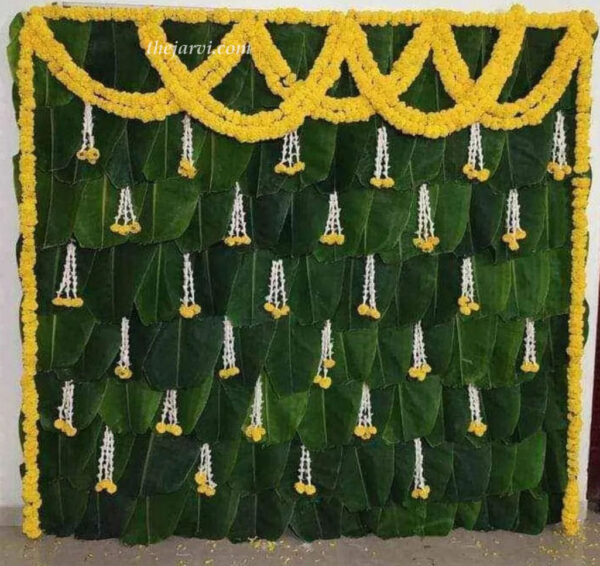 Banana leaf Haldi/Mehendi dÃ©cor with natural string marigold flower all around backdrop (except ground side), 30-35 thin three Rajnigandha attached with marigold flowers and on top side two string set one side to another side.