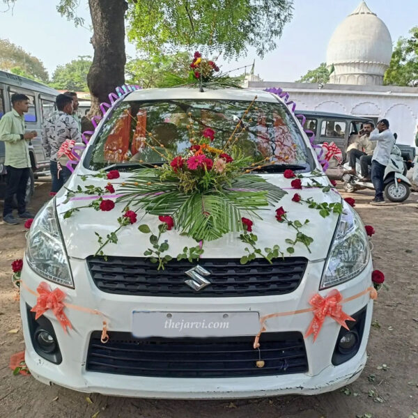 White car decoration for wedding with 1 flower bouquet with leaves on roof, 1 flower bouquet with leaves on car bonnet , 40 red rose, 4 pink bow ribbons front and back of the car, 2 curl ribbon on the roof of all gate