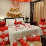first night room decoration with Just Married Foil, Love Foil, Heart Shaped Balloon, 100 Red And White Balloons Hanging From The Ceiling And Spread On The Floor and Rose Petals