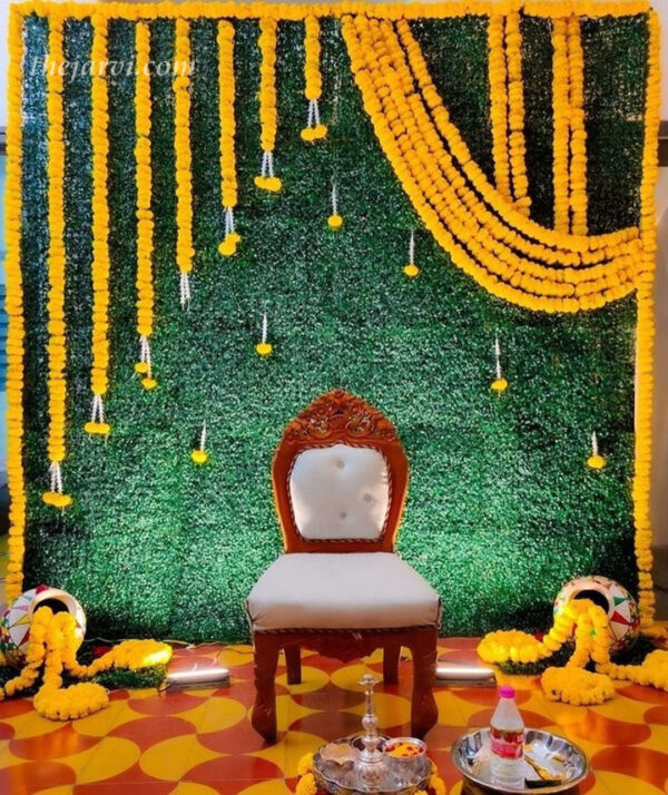 Designing dreams: mehndi decor solutions with green backdrop, 25 orange marigold flowers (long & small mix), 2 matakas (pot) and 13 small flowers hanging on backdrop made of Rajnigandha and marigold